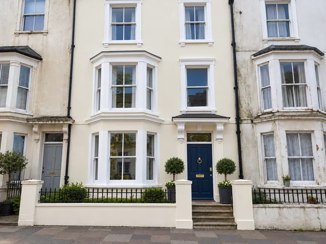 The same terrace freshly painted cream with crisp white windows and a navy front door.